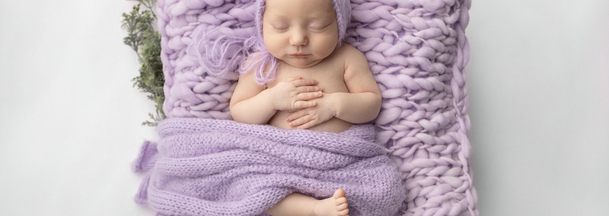baby girl laying on a lavender chunky knit blanket